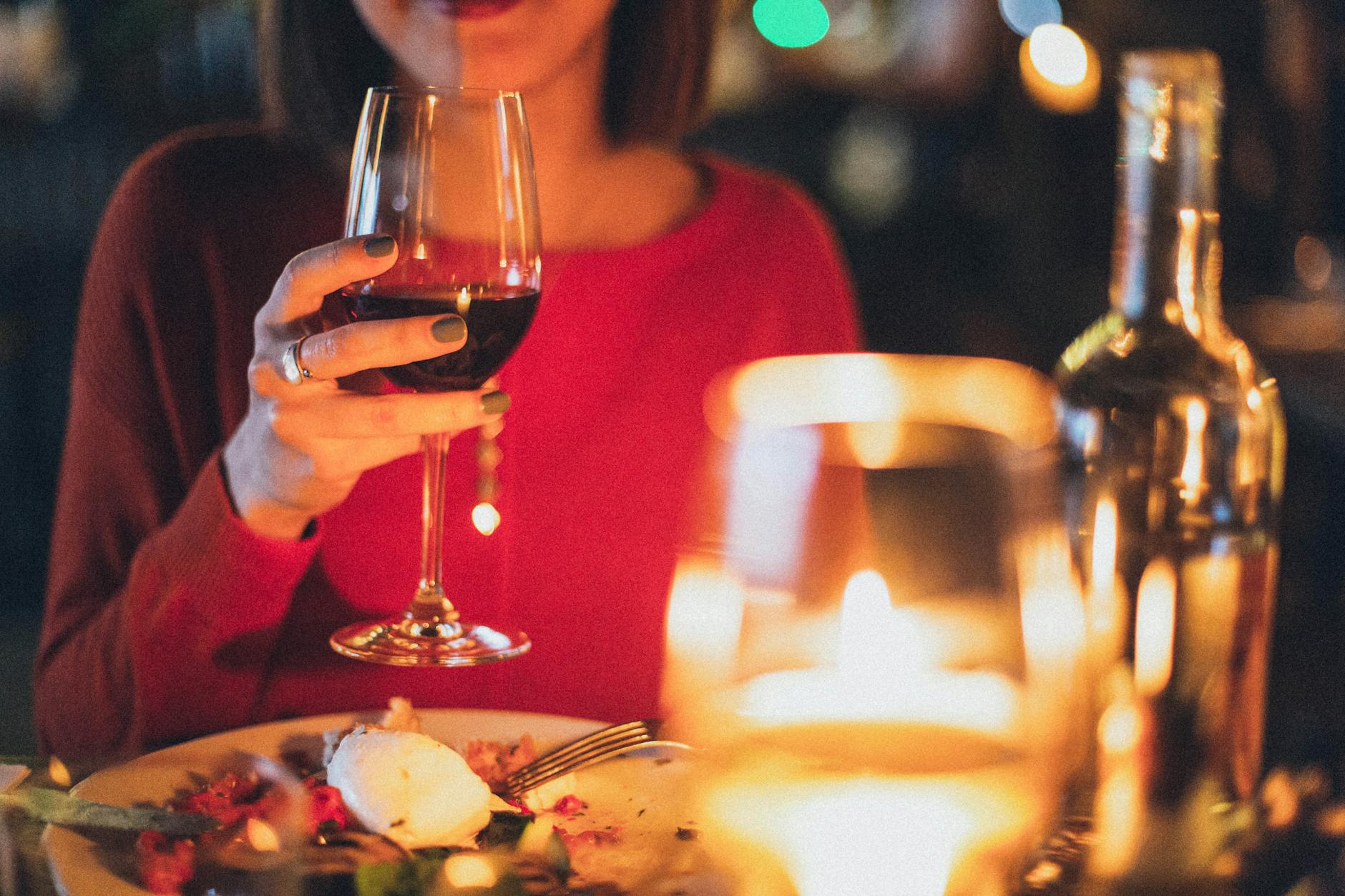 woman holding wine glass selective focus photography